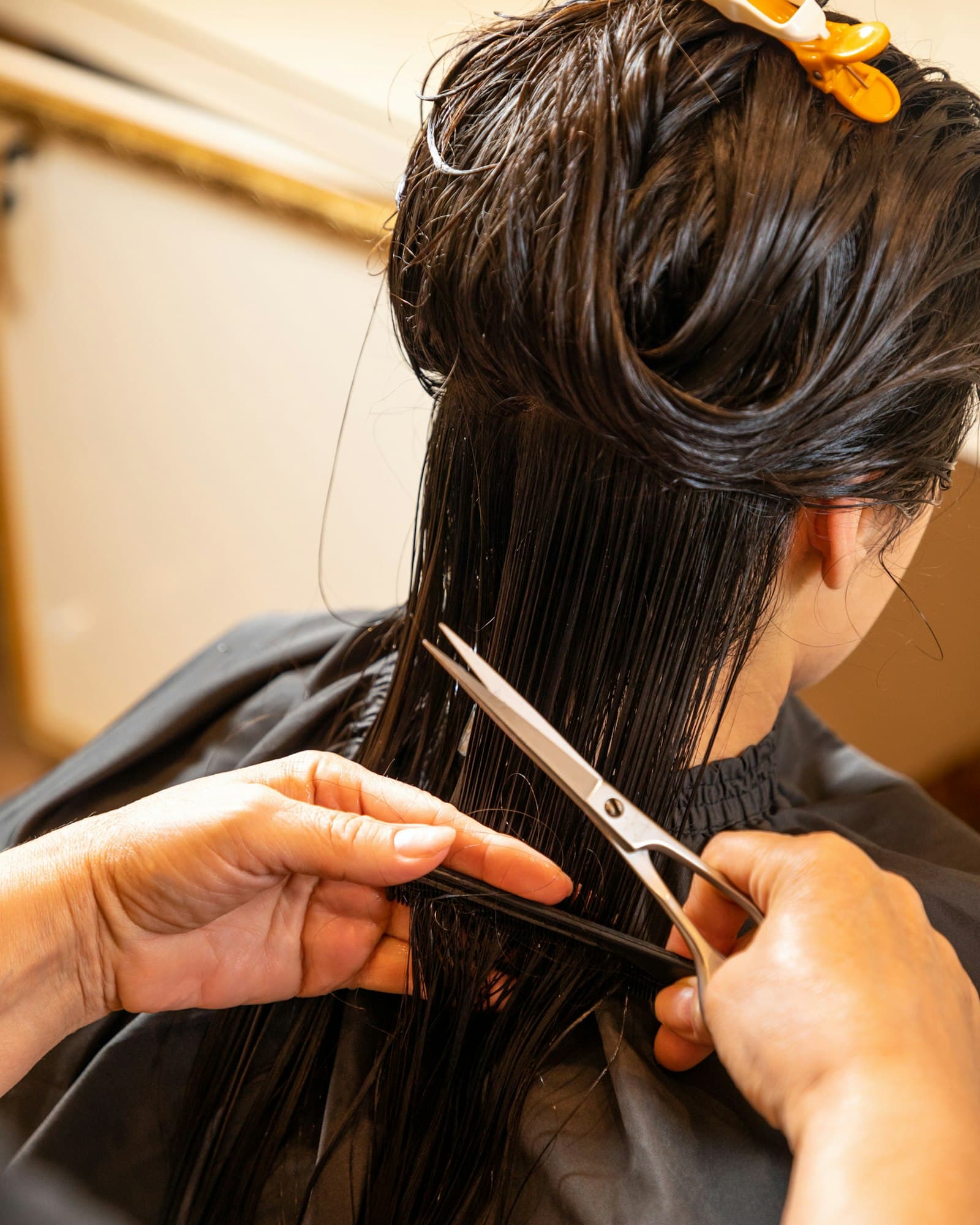 A stylist's hands shaping a client's hair with scissors
